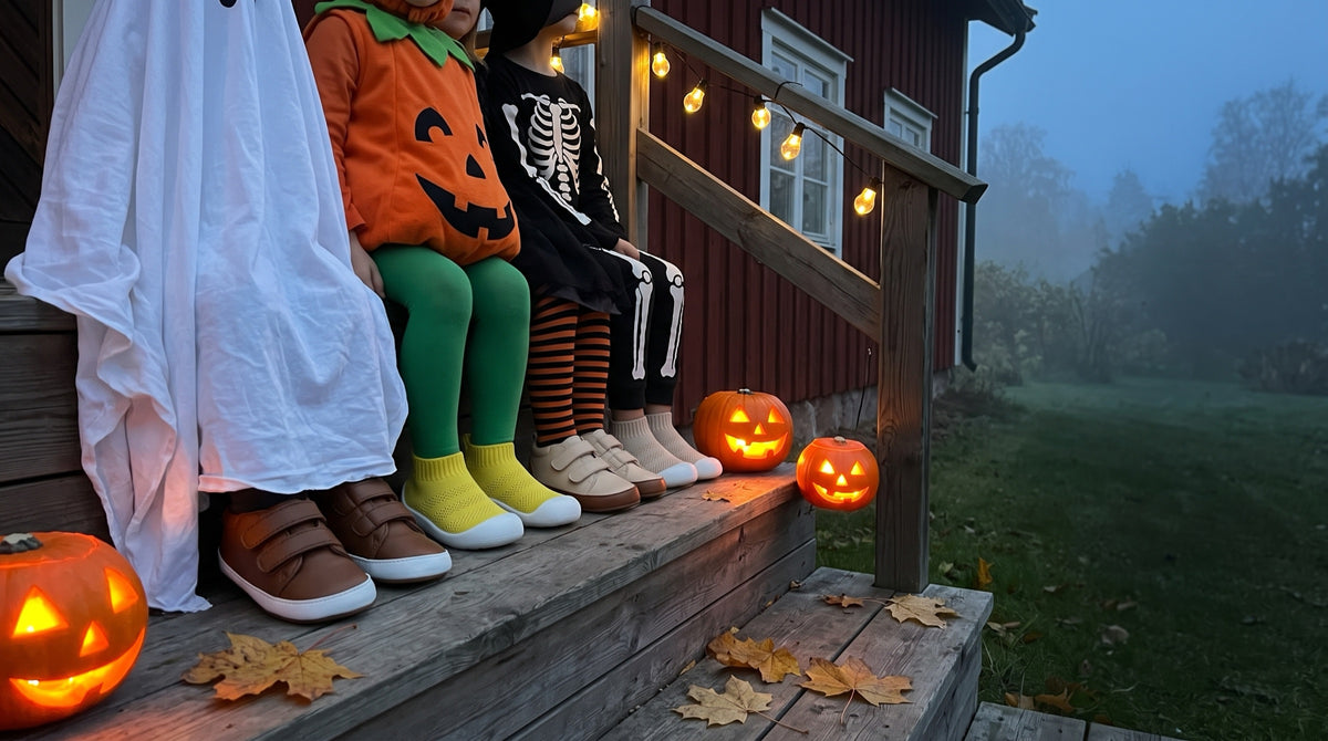 Fyra barn i Halloween-kostymer på en veranda i skymningen, med Babysteps barfotaskor