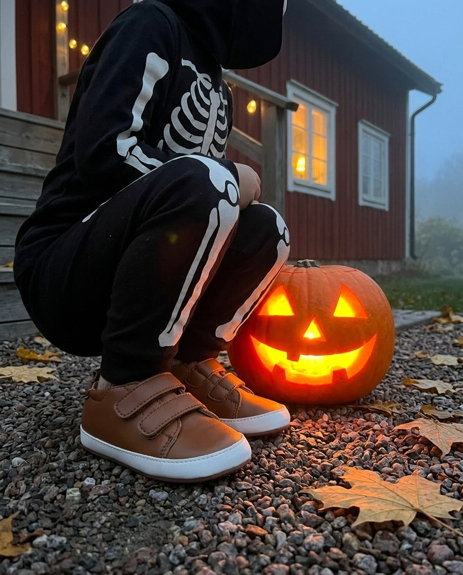 Barn utklätt till skelett bredvid en pumpa, i TabiSteps brun